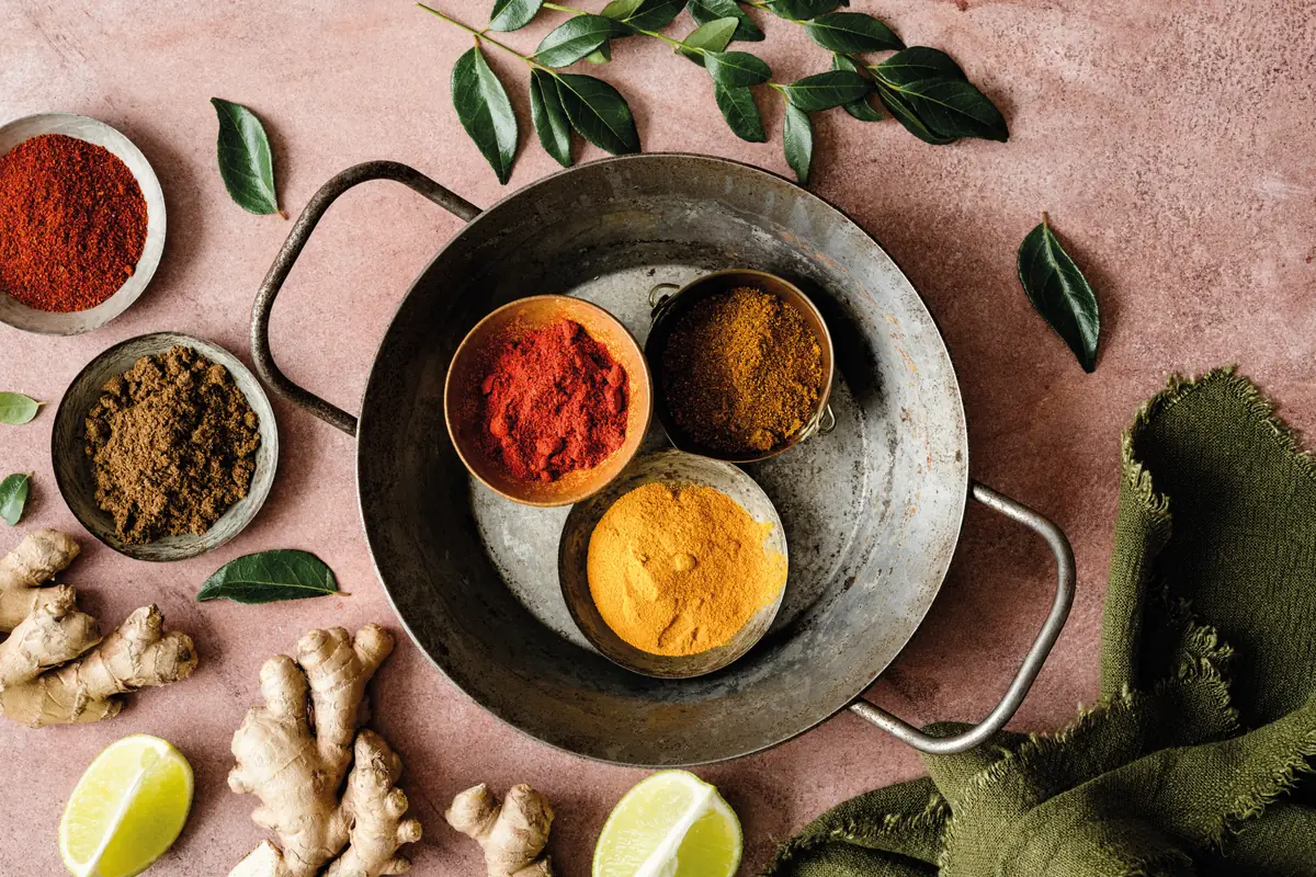 Bowls of curry spices with ginger, lime and curry leaves