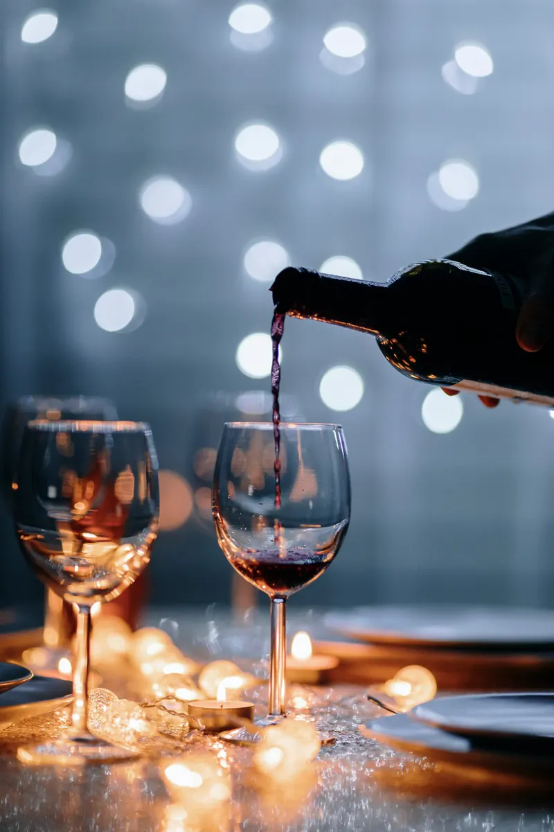 Red wine being poured into a glass by candlelight